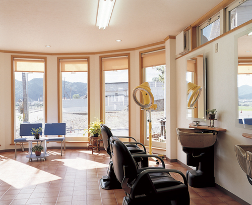 縦長のスリット窓から自然光が差し込む明るく広い理容室。